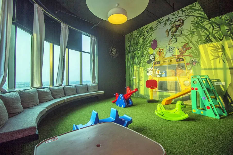 The kids&rsquo; play room at Skkky, Siliguri, with a jungle mural, slides, see-saws and a curved sofa by the windows