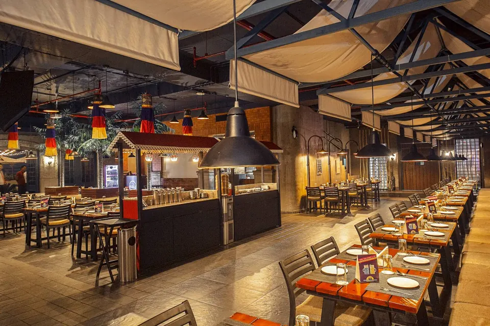 Long shared dining tables beside the live kitchen at Skkky, Siliguri