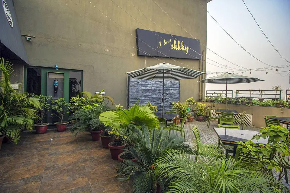 The open rooftop terrace at Skkky, Siliguri, with plants, parasols and the sky overhead